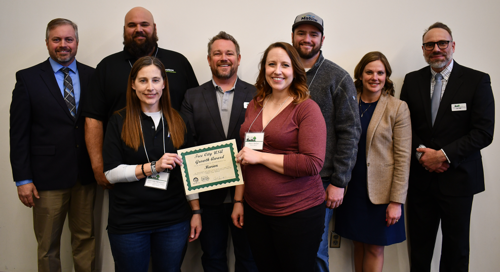 City staff, state forester, director of natural resources pose with award